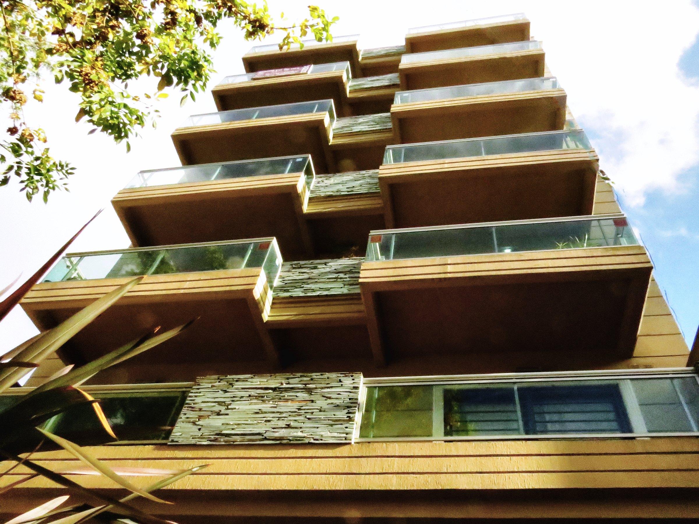 Fachada con balcones vidriados y ladrillo
