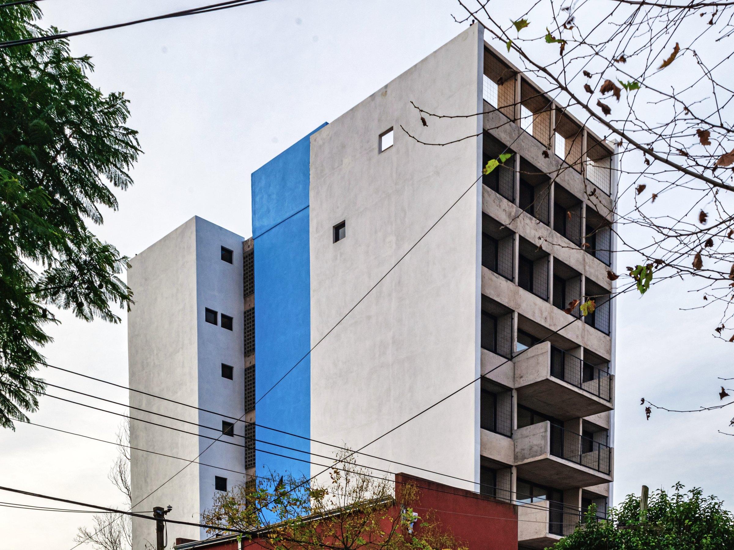 El edificio blanco con franja azul entre las medianeras