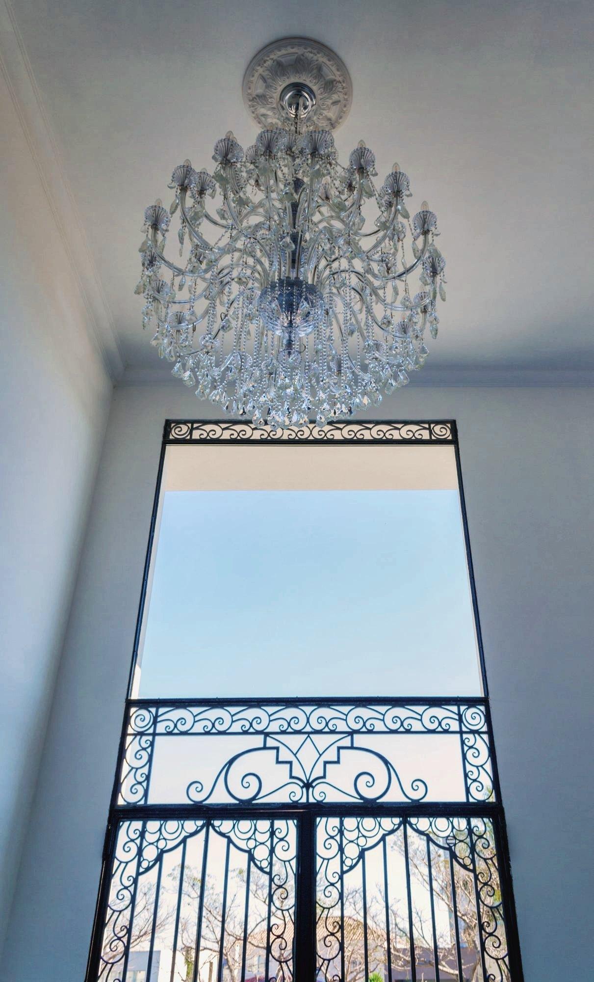 Araña de cristal y reja de hierro forjado vistas desde el hall